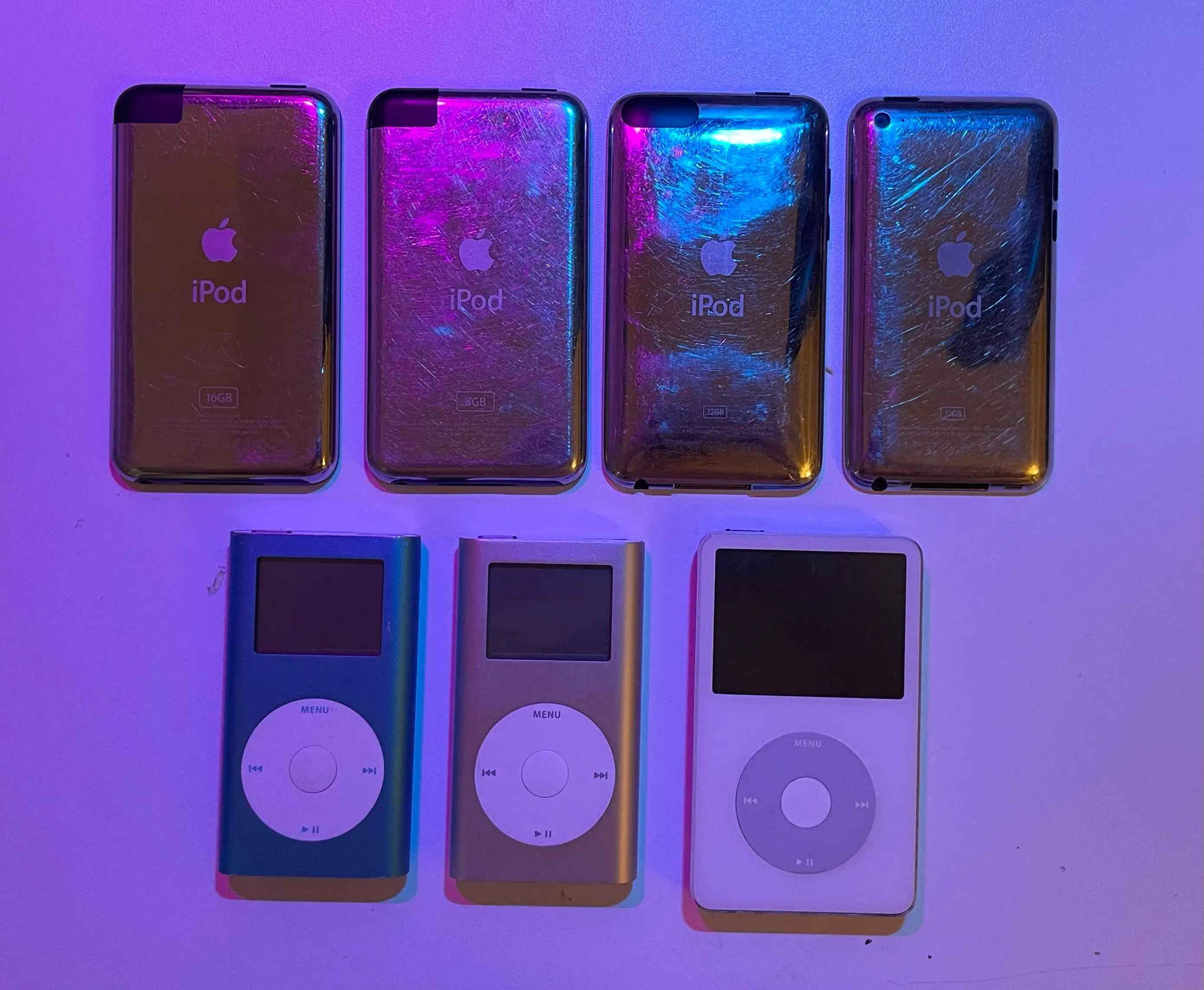 A picture showing an a few Apple iPods on a desk.